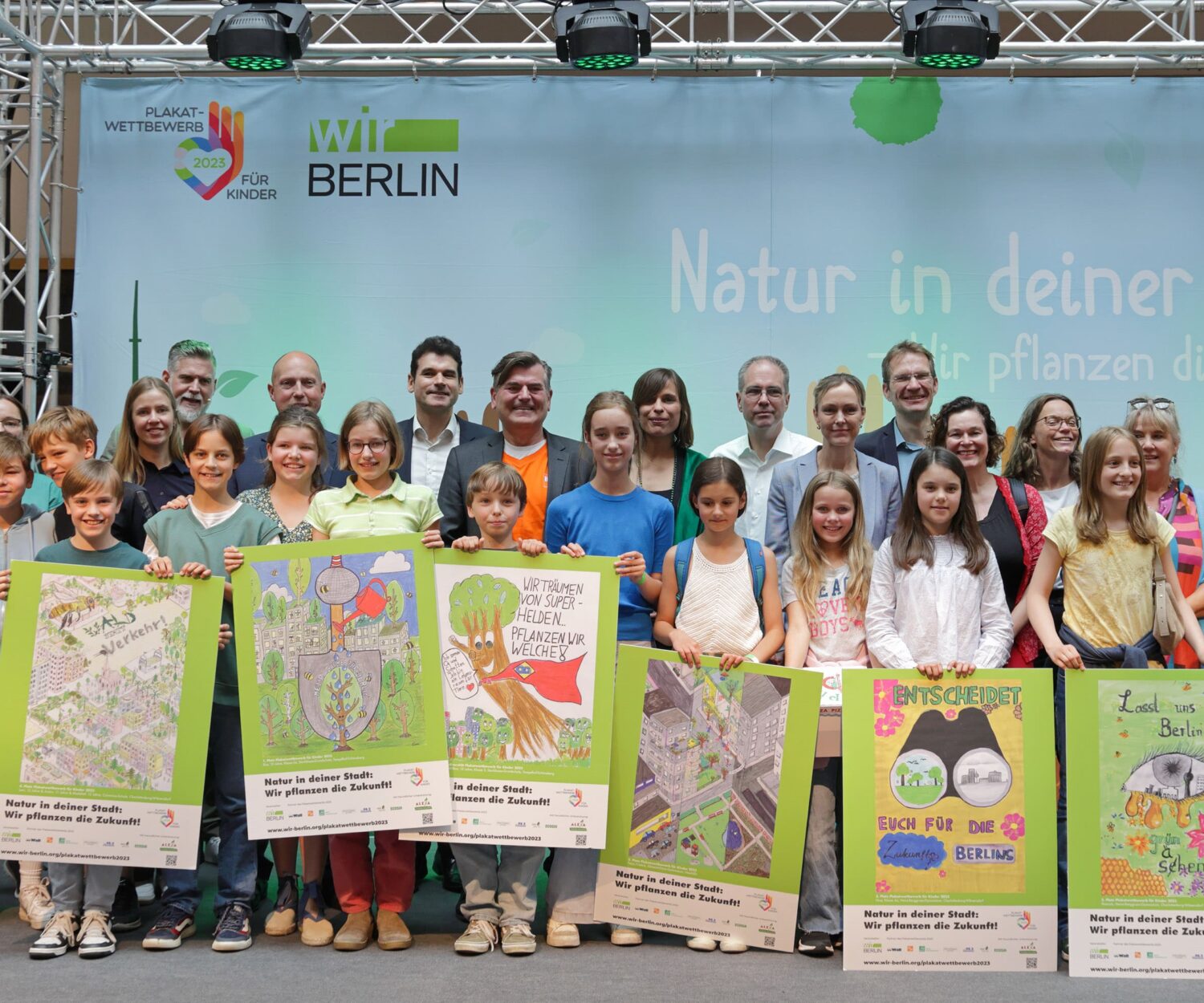 Auf einer „große Bühne“ im ALEXA Shopping wurden die Gewinner des Berlin weiten Plakatwettbewersb der Initiative wirBerlin zum Thema „Natur in der deiner Stadt“ gekürt. In der vorderen Reihe sind Kinder mit ihren Plakaten zu sehen, dahinter Personen aus dem Event-Team, Centermanagement, Partnerunternehmen, Medien und berliner Senat.