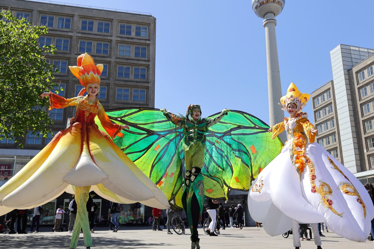 Im ALEXA Shoppingcenter am Berliner Alexanderplatz wurde das Event „Frühlingsjazz mit verkaufsoffenem Sonntag“ inszeniert. Bunte Stelzenläufer in Blumen-Outfits laufen auf dem Alexanderplatz und posieren für die Zusachuer.