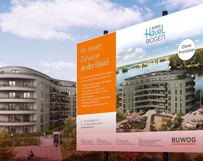 Großes Bauschild im Vordergrund, darin abgebildet ist links eine orange Fläche mit der Überschrift „Ihr neues Zuhause an der Havel“, eine Beschreibung des abgebildeten Gebäudes und Kontaktdaten, rechts ist ein 5 stöckiges Gebäude mit Sonnenkollektoren auf dem Dach abgebildet. Das Gebäude ist von Bäumen und Gras umgeben, im Hintergrund fließt ein Fluss durch eine Naturlandschaft. Oben auf dem Schild befindet das Logo mit den Worten „BUWOG HAVELBOGEN”. Hinter dem Bauschild befindet sich verschwommen ein Gebäude mit Bäumen, Wegen und Gras unter einem Blau-bewölkten Himmel.