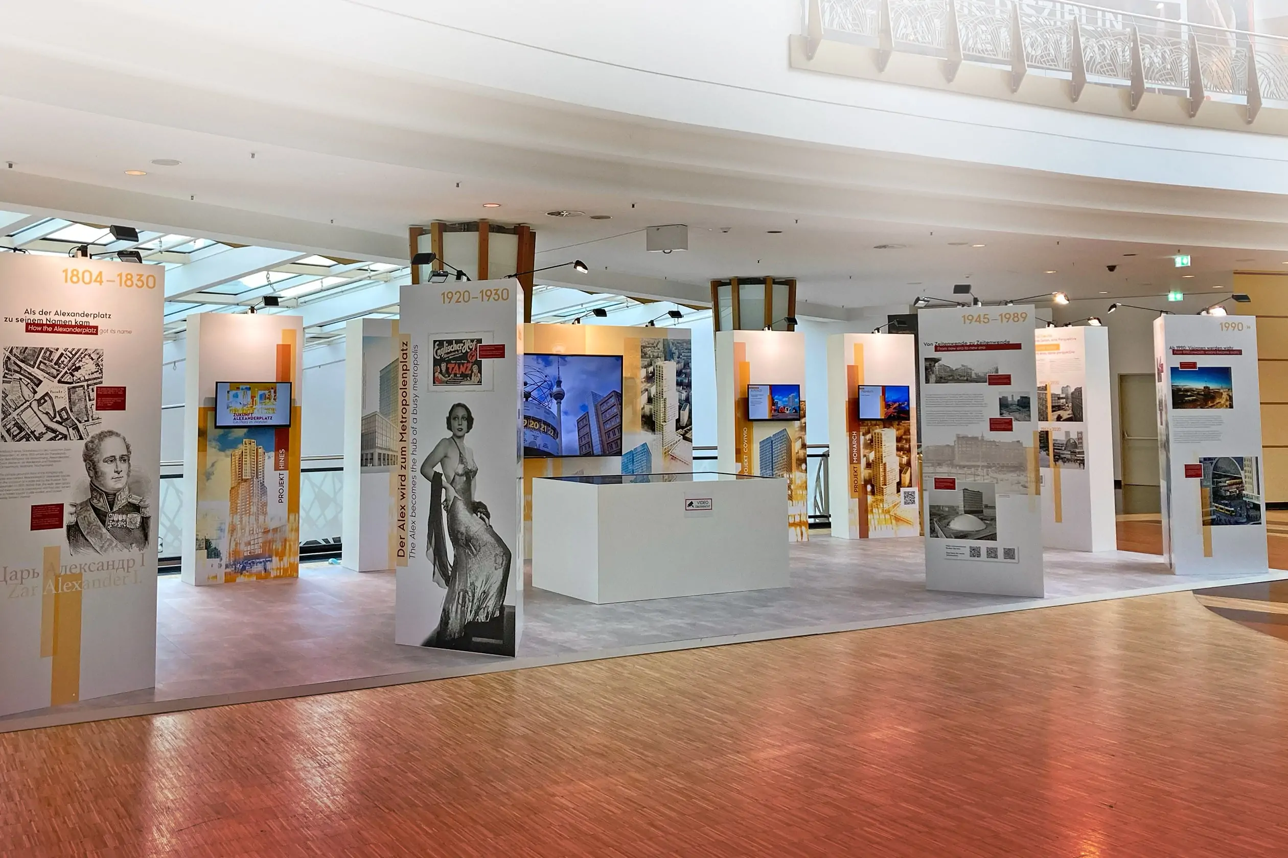 Im Innenraum des ALEXA Shopping Centers findet die Ausstellung „ZUKUNFT ALEXANDERPLATZ. EIN PLATZ im WANDEL.“ statt. Zu sehen sind dreieckige Stellwände mit historischen Figuren und Fotos vom Alexanderplatz, dahinter rechteckige Stellwände mit integrierten Bildschirmen, auf welchen Videos über die Gegenwart und Zukunft vom Alexanderplatz informiert wird.