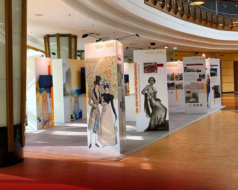 Im Innenraum des ALEXA Shopping Centers findet die Ausstellung „ZUKUNFT ALEXANDERPLATZ. EIN PLATZ im WANDEL.“ statt. Zu sehen sind dreieckige Stellwände mit historischen Figuren und Fotos vom Alexanderplatz, dahinter rechteckige Stellwände mit integrierten Bildschirmen, auf welchen Videos über die Gegenwart und Zukunft vom Alexanderplatz informiert wird.